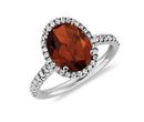 A garnet engagement ring of an oval gemstone center surrounded by diamond halo set in white gold
